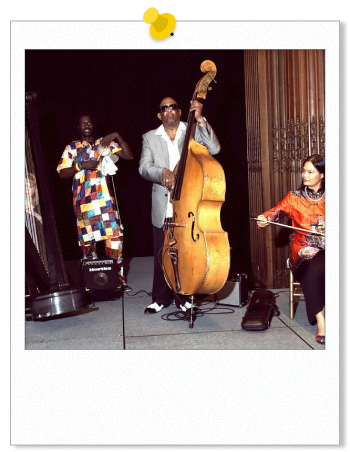 Photo of a band, including a harpist, bassist, and a Chinese Erhu player, at the 2019 World Heritage City Celebration.